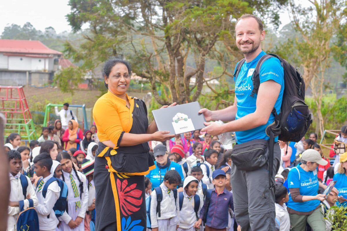 Membro del Gruppo Xera e donna locale dello Sri Lanka sorreggono insieme l'agenda WEEKO durante una missione in Sri Lanka con l'organizzazione no-profit Take Me Back.