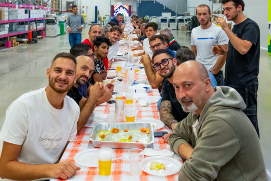 Dipendenti di Gruppo Xera seduti a tavola posano per una foto insieme