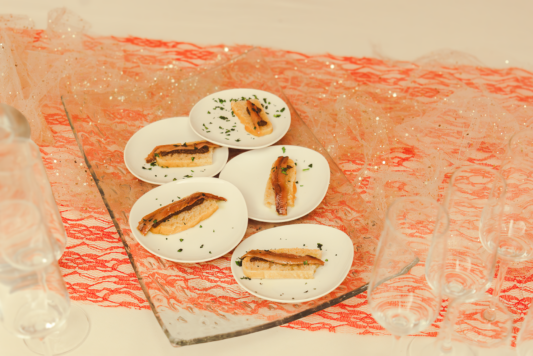 Cinque piatti con bruschetta e salmone poggiati su un tavolo
